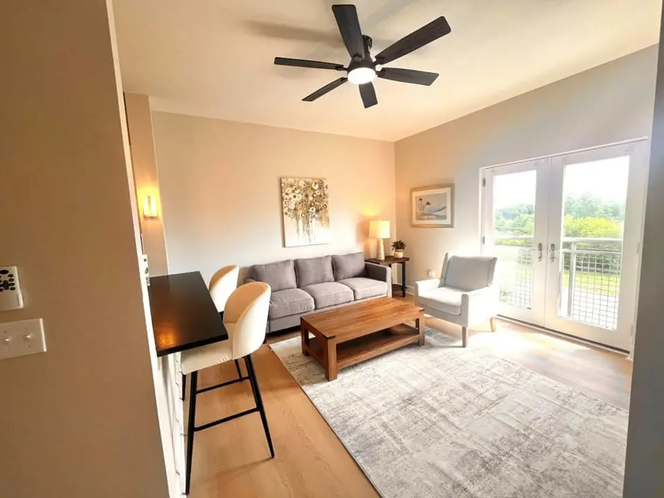 Living room with a ceiling fan and French doors onto a balcony